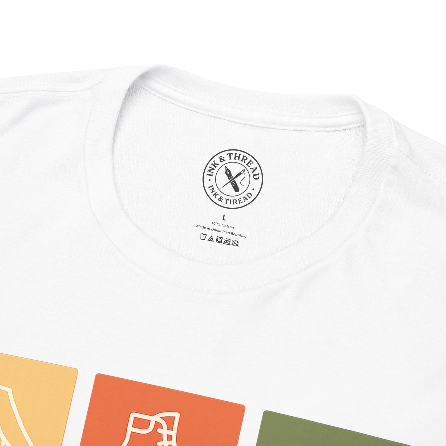 Close-up of Ink and Thread UK inner neck label on white t-shirt showing brand stamp size and care instructions with colour swatches below