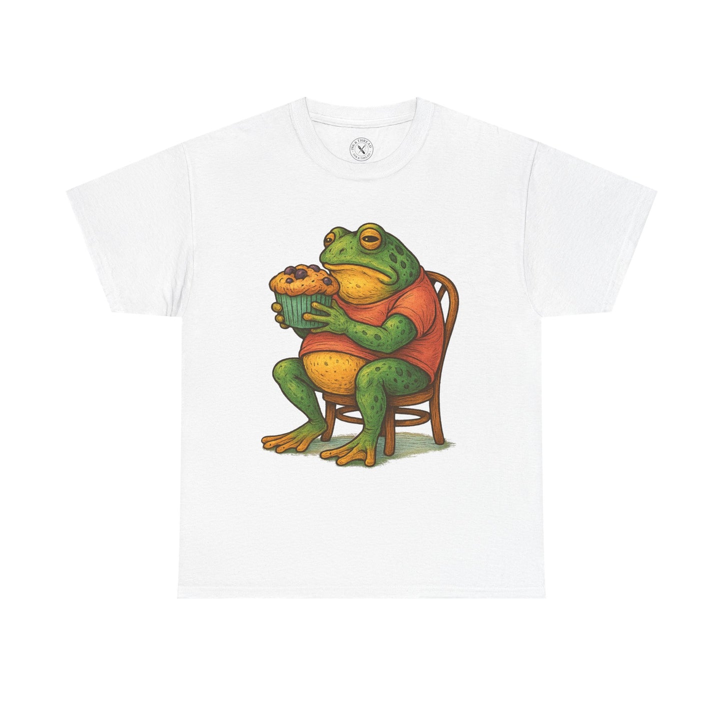 White t-shirt with a frog graphic holding a cupcake on a white background