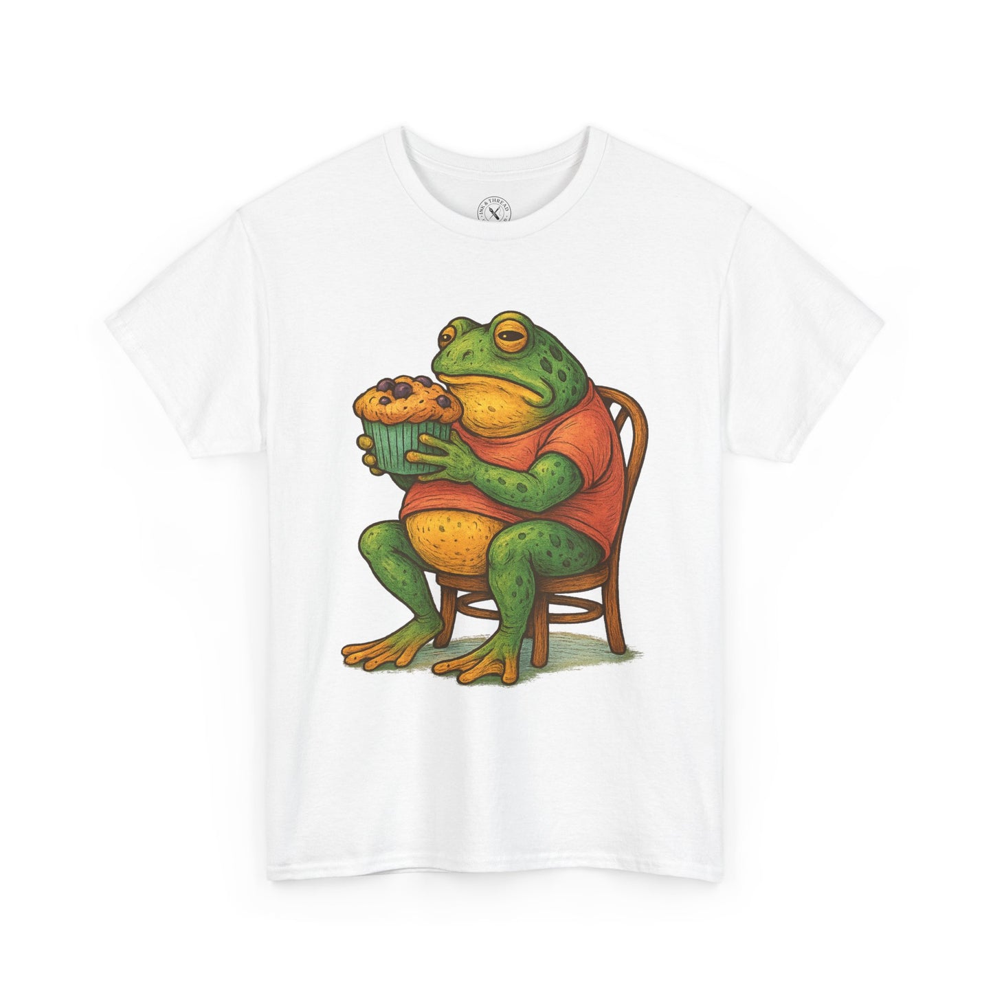 White t-shirt with a colorful frog graphic holding a cupcake on a white background