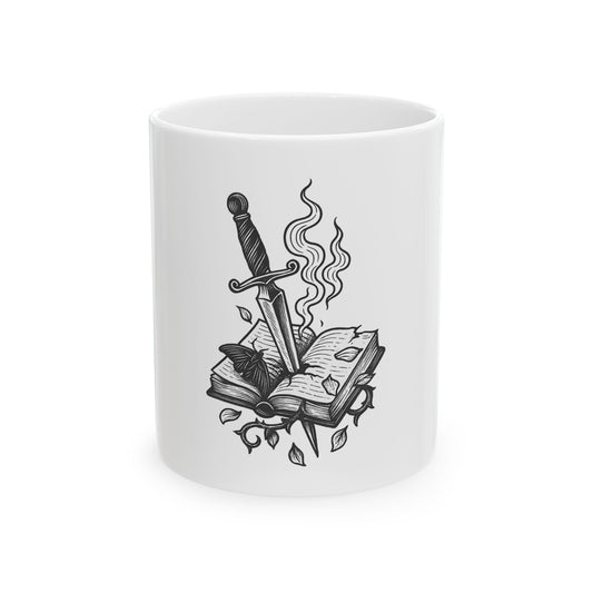 White mug with black ink design of a sword, book, and leaves on a white background