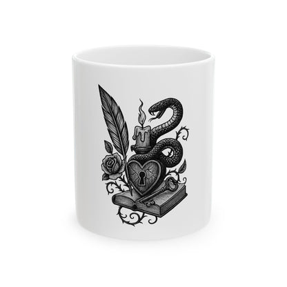 White mug with black decorative design featuring a snake, heart, and book on a white background