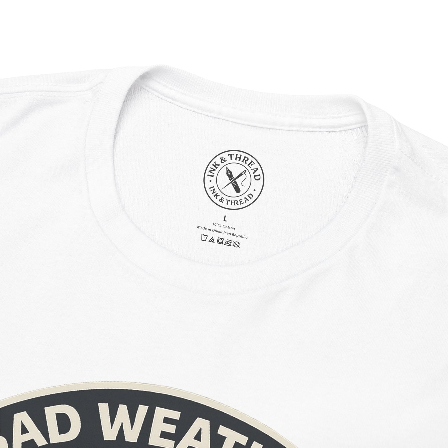 Close-up of Ink and Thread UK branded inner neck label on white t-shirt with Bad Weather Builds Character camping graphic design and care instructions