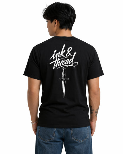 Male model wearing Ink & Thread UK black t-shirt from the back showing script logo and dagger graphic