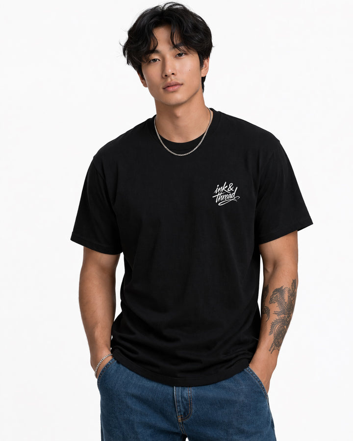 Male model wearing Ink & Thread UK black t-shirt from the front with script logo on chest