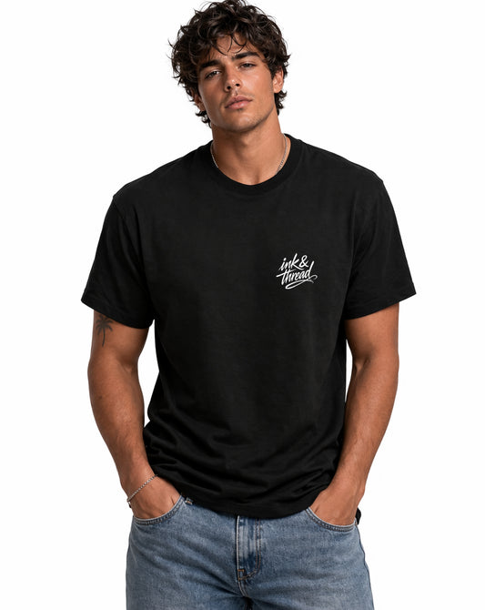 Male model wearing Ink & Thread UK black t-shirt from the front with script logo on chest