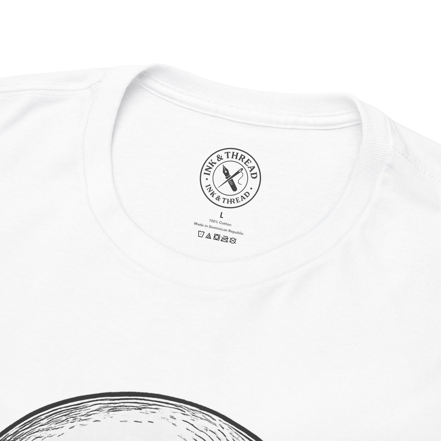 Close-up of Ink and Thread UK branded neck label on white t-shirt showing size tag and care instructions