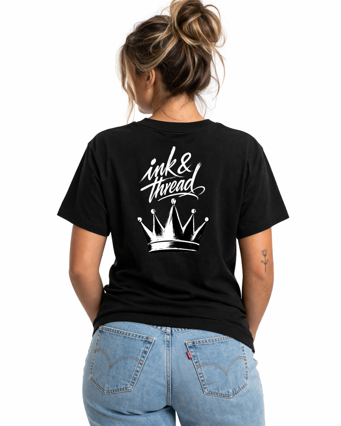Woman model wearing Ink & Thread UK black t-shirt showing back design with script logo and crown graphic