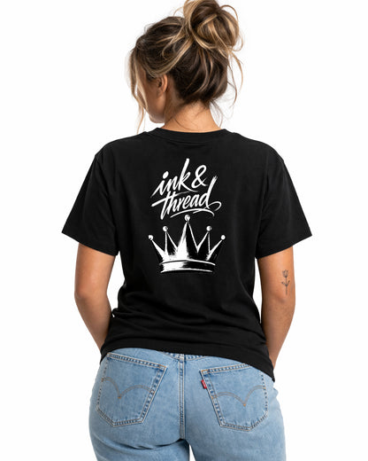 Woman model wearing Ink & Thread UK black t-shirt showing back design with script logo and crown graphic