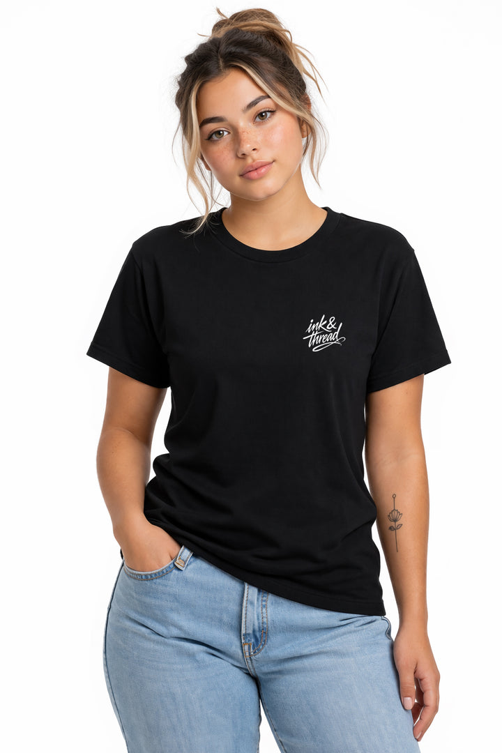 Woman model wearing Ink & Thread UK black t-shirt from the front with small white script logo on chest