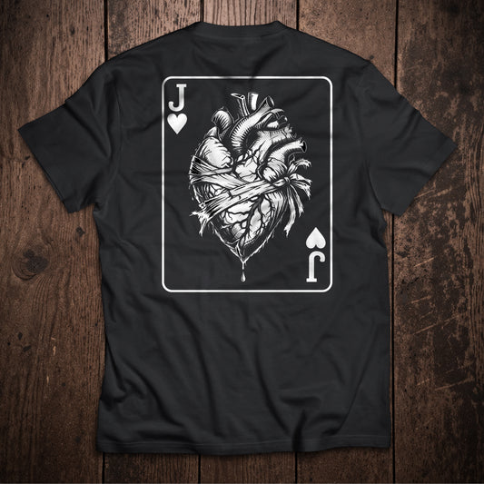 Black t-shirt flat lay on wooden surface with Jack of Hearts playing card design featuring anatomical heart illustration