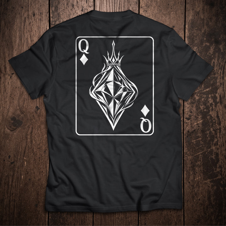 Black t-shirt flat lay on wooden surface with Queen of Diamonds playing card design featuring crowned geometric diamond illustration
