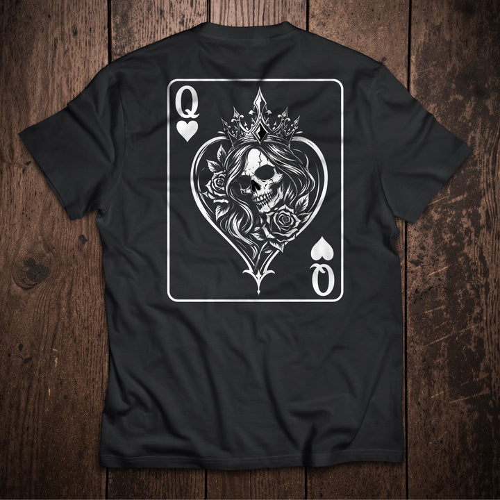 Black t-shirt flat lay on wooden surface with Queen of Hearts playing card design featuring crowned skull with roses illustration