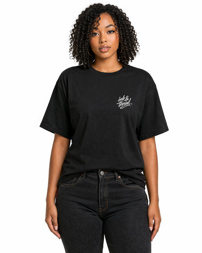 Female model wearing black t-shirt with Ink and Thread script logo on left chest against white background