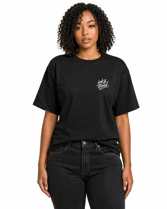 Female model wearing black t-shirt with Ink and Thread script logo on left chest against white background