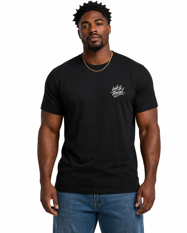 Male model wearing black t-shirt with Ink and Thread script logo on left chest against white background