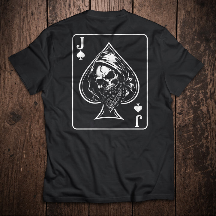 Black t-shirt flat lay on wooden surface with Jack of Spades playing card design featuring skull and grim reaper illustration